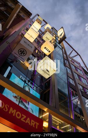 VIENNE, AUTRICHE - 10 AOÛT 2024 : des enseignes de marque de mode de luxe illuminent la rue commerçante Kohlmarkt en soirée. Des marques célèbres comme Moschino, Dolce Banque D'Images