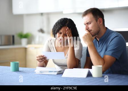 Triste couple ou colocataires vérifiant le relevé bancaire dans la cuisine à la maison Banque D'Images