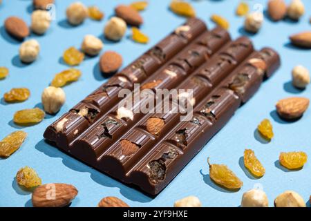 Chocolat au lait de noisette parmi les amandes, raisins secs et noisettes éparpillées. Banque D'Images