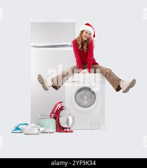 Magasin d'appareils ménagers magasin de Noël : femme heureuse assise sur une machine à laver, jouant un coup de pied dans les jambes, Top deals et ventes dans un supermarché Banque D'Images