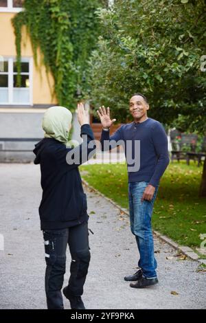 Main mature souriante agitant la voisine féminine tout en se tenant sur le sentier dans le jardin Banque D'Images