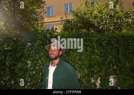 Portrait d'un jeune homme debout contre un mur couvert de plantes Banque D'Images