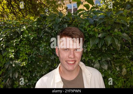 Portrait d'un jeune homme souriant debout contre des plantes Banque D'Images
