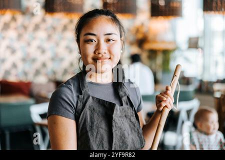 Portrait d'une serveuse souriante tenant une serpillière Banque D'Images