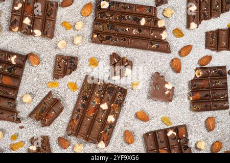 Morceaux de chocolat cassés avec des noix et des raisins secs sur une vue de dessus de fond en pierre Banque D'Images