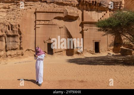 AL ULA, ARABIE SAOUDITE - 9 NOVEMBRE 2021 : homme local à côté des tombes taillées dans la roche 39 et 40 sur la colline Jabal Al Banat sur le site de Hegra (Mada'in Salih) près d'Al U. Banque D'Images