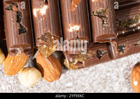 Morceaux de chocolat cassés avec des noix et des raisins secs sur une vue de dessus de fond en pierre Banque D'Images