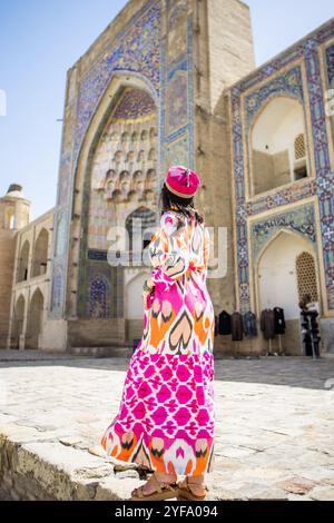 Vue arrière de la jeune femme debout devant la Madrasah dans le centre historique Boukhara, Ouzbékistan Banque D'Images