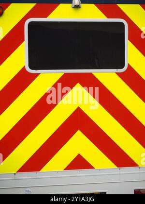 Bandes de danger ou d'avertissement à motif chevrons rouges et jaunes à l'arrière du véhicule avec vitre noire. Format vertical ou portrait. Banque D'Images