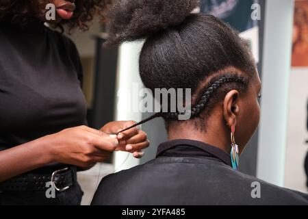 Coiffeur tressant les cheveux afro du client dans le salon Banque D'Images