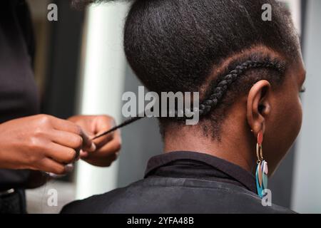 Coiffeur faisant des tresses au crochet sur cheveux afro dans un salon Banque D'Images