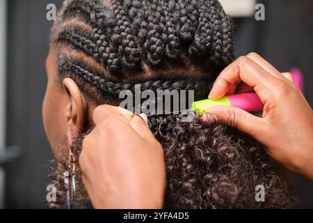 Coiffeur faisant des tresses au crochet sur le client avec des cheveux afro Banque D'Images