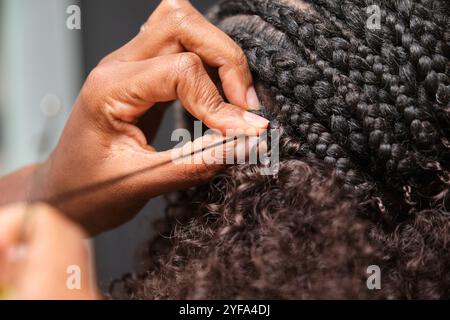 Coiffeur fabriquant des tresses au crochet dans un salon de coiffure afro Banque D'Images