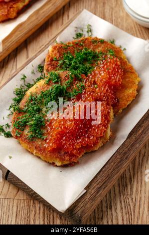 crêpes de pommes de terre au caviar rouge sur une assiette en bois Banque D'Images