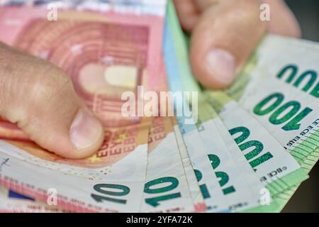 Gros plan des mains comptant la pile de billets en euros. Homme tenant du papier-monnaie en espèces. Concept de gestion de trésorerie, de patrimoine ou de transactions financières Banque D'Images