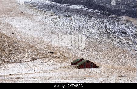 Paysage islandais typique de la péninsule de Reykjavik avec des montagnes couvertes de neige et des maisons de stockage solitaire dans le champ Banque D'Images