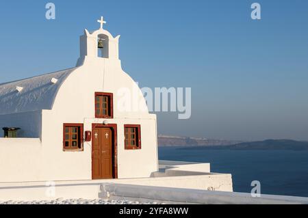 Petite église blanche traditionnelle au coucher du soleil village d'Oia en mer Égée sur l'île grecque de Santorini en Grèce Banque D'Images