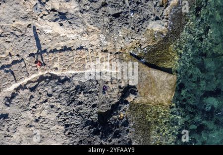 Fait vue de gens méconnus marchant sur une plage rocheuse. Mer calme idyllique. Cap Grego Chypre Banque D'Images