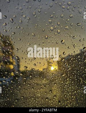 Gouttes de pluie sur la fenêtre en verre au coucher du soleil. Attendez la fenêtre pluvieuse Banque D'Images