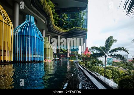 Singapour - 16 août 2024 : Park Royal Collection Pickering Hotel piscine à débordement avec plantes tropicales et lodges colorés Banque D'Images