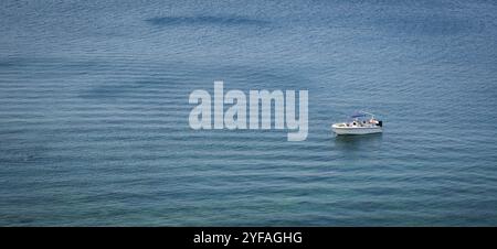 Petit yacht de vacances isolé amarré dans l'océan. Eau de mer bleue et calme idyllique. Paysage marin panoramique Banque D'Images