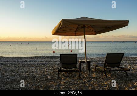 Parasols de plage et chaises de détente en mer au lever du soleil. Plage vide le matin Pissouri Chypre Banque D'Images