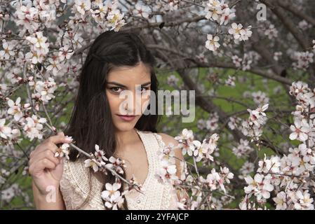 Young caucasian belle dame, habillée de vêtements rose, appréciant les fleurs de prunier. Concept de l'accueil Printemps Banque D'Images