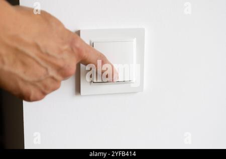 La main d'un homme allume la lumière dans l'appartement Banque D'Images