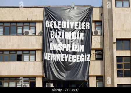 Diyarbakir, Turquie. 04th Nov, 2024. Une banderole noire indiquant «les municipalités sont à nous, nous ne permettrons pas l'usurpation» a été accrochée sur le bâtiment de la municipalité métropolitaine de Diyarbakir pour protester contre la nomination des administrateurs pour remplacer Ahmet Turk, co-maire de Mardin, Gulistan Sonuk, co-maire de Batman et Mehmet Karayilan, co-maire du district de Halfeti, qui ont été élus du Parti de l'égalité des peuples et de la démocratie (Parti DEM). Crédit : SOPA images Limited/Alamy Live News Banque D'Images