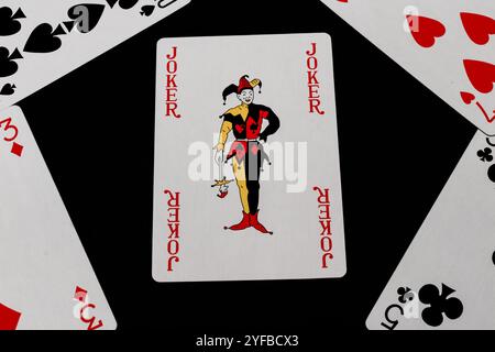 Carte Joker entourée de cartes à jouer sur un fond noir, journée nationale de jeu de cartes Banque D'Images