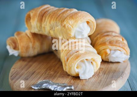 Pile de cornes de crème feuilletée de pâte feuilletée, Cannoncini, fourrées de crème vanille sur table rustique. Mise au point sélective avec arrière-plan flou. Banque D'Images