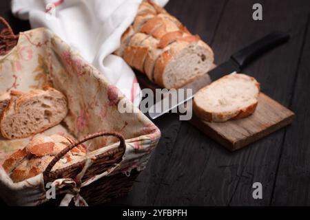 Présentoir de pain rustique avec pain de grain entier tranché dans un panier en osier sur une table en bois - parfait pour les thèmes de décoration de boulangerie, culinaire et ferme Banque D'Images