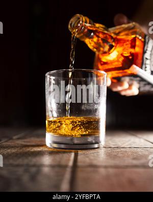 Un gros plan de whisky versé dans un verre, mettant en valeur la riche couleur ambre et l'élégance de cet esprit classique. Banque D'Images