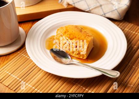 flan dessert, recette maison facile aussi connue sous le nom de crème caramel, pudding à la crème anglaise au caramel ou crème anglaise aux œufs, servi sur assiette blanche sur table en bois. Banque D'Images