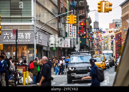 Une scène de rue animée dans Chinatown, New York City, avec circulation dense, piétons, lanternes colorées, et des vitrines vibrantes. Banque D'Images