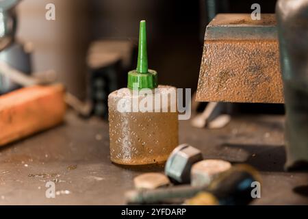 Bouteille d'huile lubrifiante sur un établi entouré d'outils et de fixations métalliques. Banque D'Images