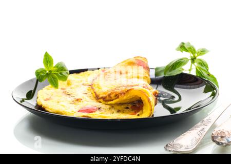 omelette frite au poivron doux et légumes dans une assiette, isolée sur fond blanc. Banque D'Images