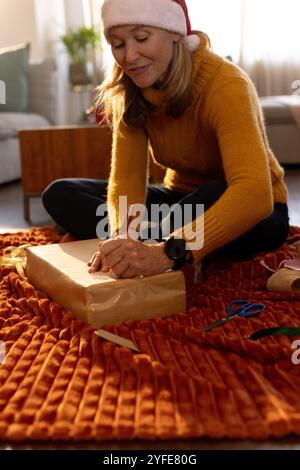 Emballage cadeau de Noël, femme senior souriant pendant les préparatifs de vacances à la maison Banque D'Images