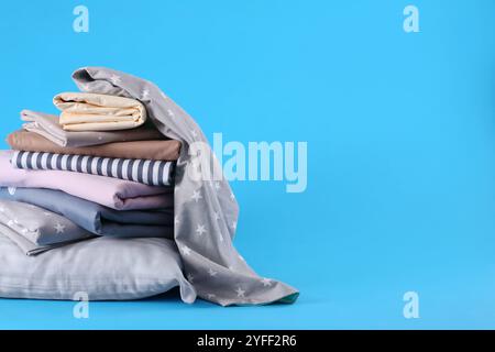 Pile de draps propres et d'oreillers sur fond bleu. Espace pour le texte Banque D'Images