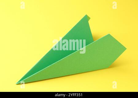 Un avion de papier vert fait à la main sur fond jaune, gros plan Banque D'Images