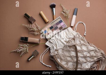 Sac à provisions en macramé fait à la main avec des produits de maquillage et des pointes sur fond brun, plat Banque D'Images