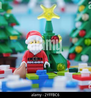 Tambov, Fédération de Russie - 04 novembre 2024 Une figurine Lego Santa Claus avec un sac de cadeaux debout devant un arbre de Noël et surroun Banque D'Images