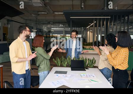 Une équipe diversifiée de professionnels applaudit un collègue après une présentation réussie au bureau Banque D'Images