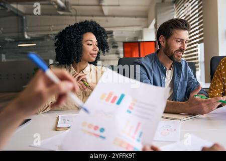 Jeunes professionnels travaillant ensemble au bureau, analysant les données marketing et discutant de nouvelles stratégies Banque D'Images