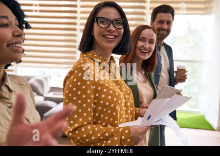 Groupe de quatre hommes d'affaires tiennent des documents et sourient dans un bureau moderne Banque D'Images