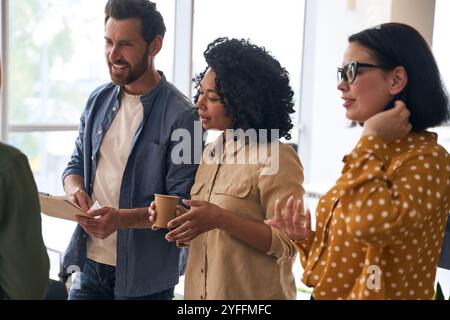 Un groupe de gens d'affaires multi-ethniques se tient dans le bureau, brainstorming et discute de nouvelles idées Banque D'Images
