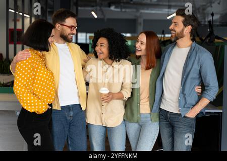 Groupe de cinq collègues se tiennent debout ensemble, les bras autour de l'autre, riant et appréciant la compagnie de l'autre Banque D'Images