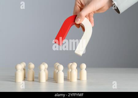 Femme avec aimant attirant des figures humaines en bois à la table lumineuse, gros plan Banque D'Images