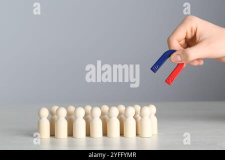 Femme avec aimant attirant des figures humaines en bois à la table lumineuse, gros plan Banque D'Images