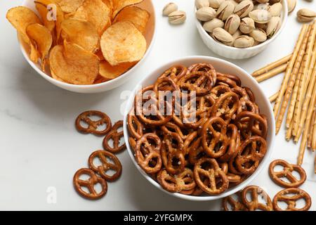 Délicieux craquelins de bretzel et autres collations sur table blanche, plat Banque D'Images